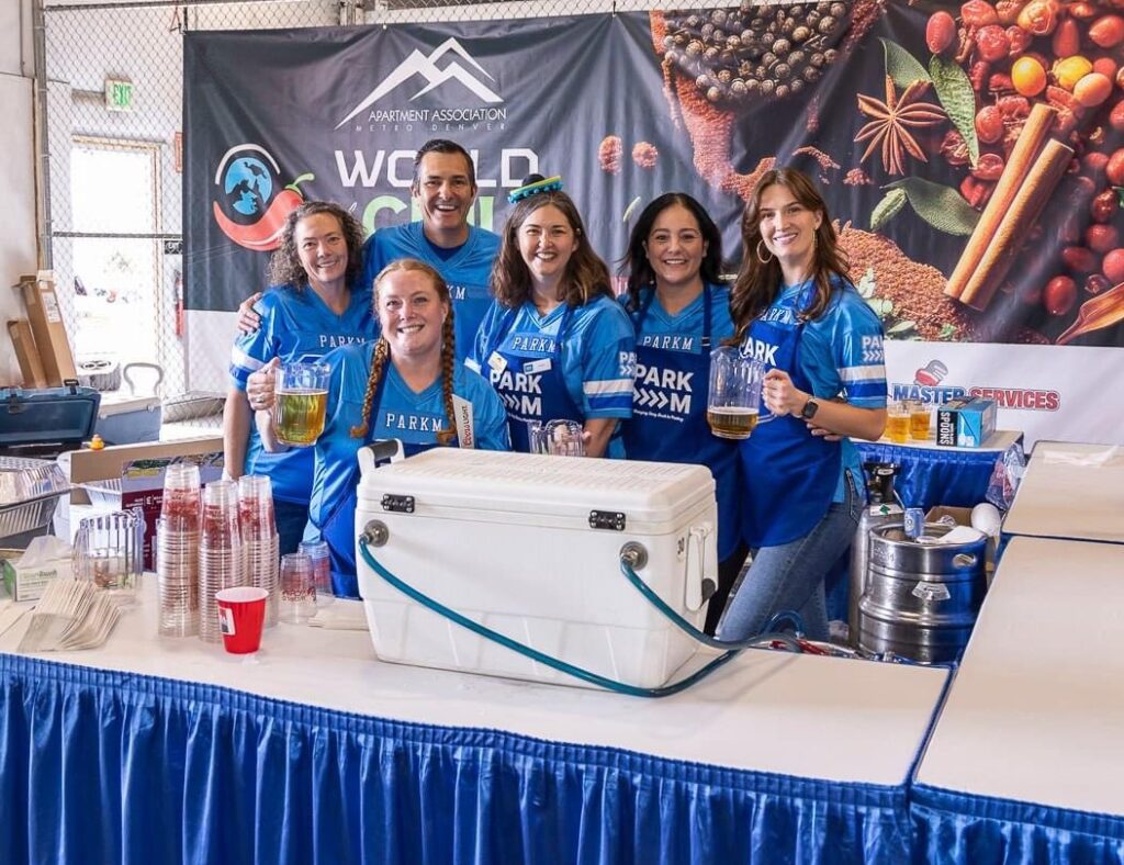 Team standing behind booth at chili cookoff apartment association event