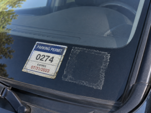 Car windshield showing an expired apartment parking permit.