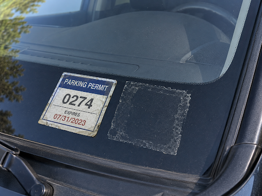 Car windshield showing an expired apartment parking permit.