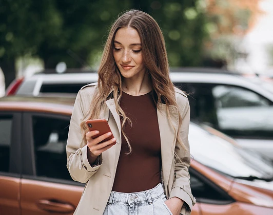 Resident checking her phone in an apartment parking lot