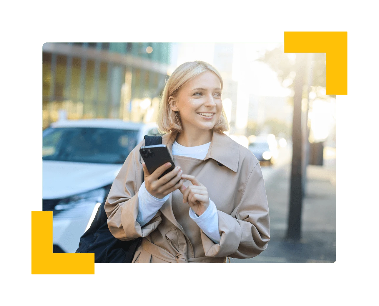 Smiling resident holding her phone on a city street beside parked cars