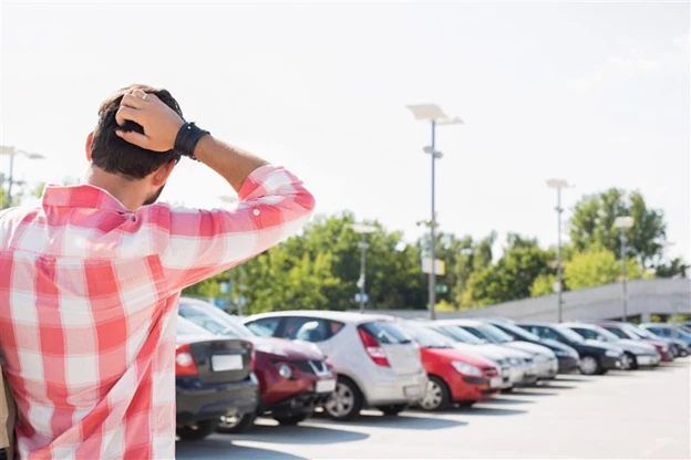 Frustrated driver with a hand on his head in a crowded parking lot