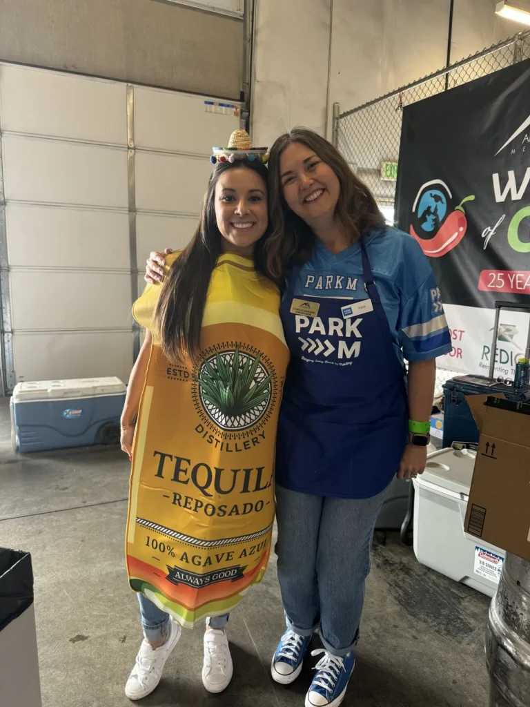 ParkM team member in a ParkM apron with a guest in a tequila bottle costume at a chili cook-off