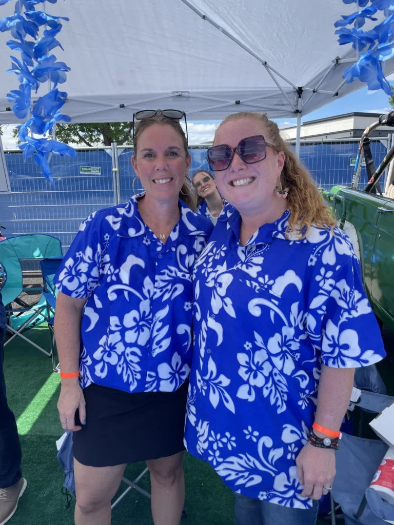 Two ParkM team members in matching blue Hawaiian shirts at a tailgate tent