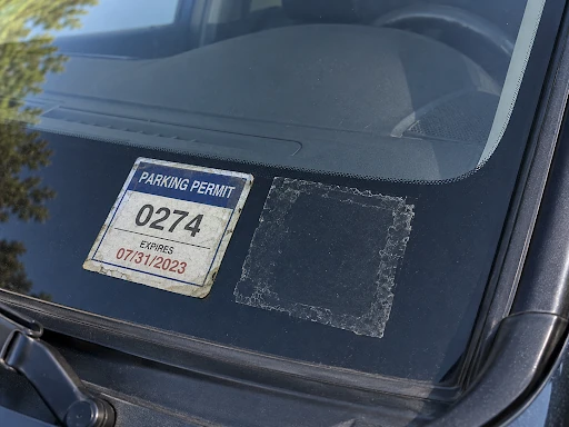 Car windshield showing an expired apartment parking permit.